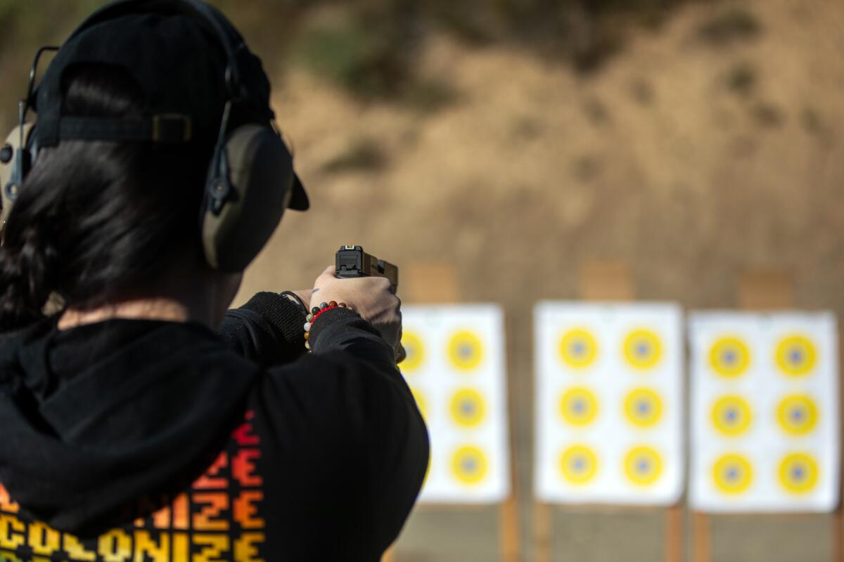 Nikki Shrieves fires a pistol at a row of paper bull's-eye targets