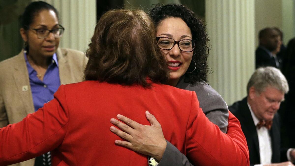 Assemblywoman Cristina Garcia (D-Bell Gardens), right, is hugged by Assemblywoman Eloise Reyes (D-Grand Terrace) on her first day back in the Assembly since an investigation into sexual misconduct charges.
