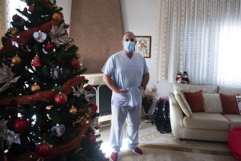 In this Saturday, Dec. 12, 2020 photo, Gabriel Tachtatzoglou poses at his home in Agios Athanassios, outside Thessaloniki city, northern Greece. Tachtatzoglou has worked as an ICU nurse in northern Greece for 20 years but when the pandemic struck his city in the fall, COVID-19 wards were quickly overwhelmed. He saw little choice other than to treat sick members of his family at home, setting up a treatment site with borrowed and rented medical machinery and using a hat stand to hold IV bags. (AP Photo/Giannis Papanikos)