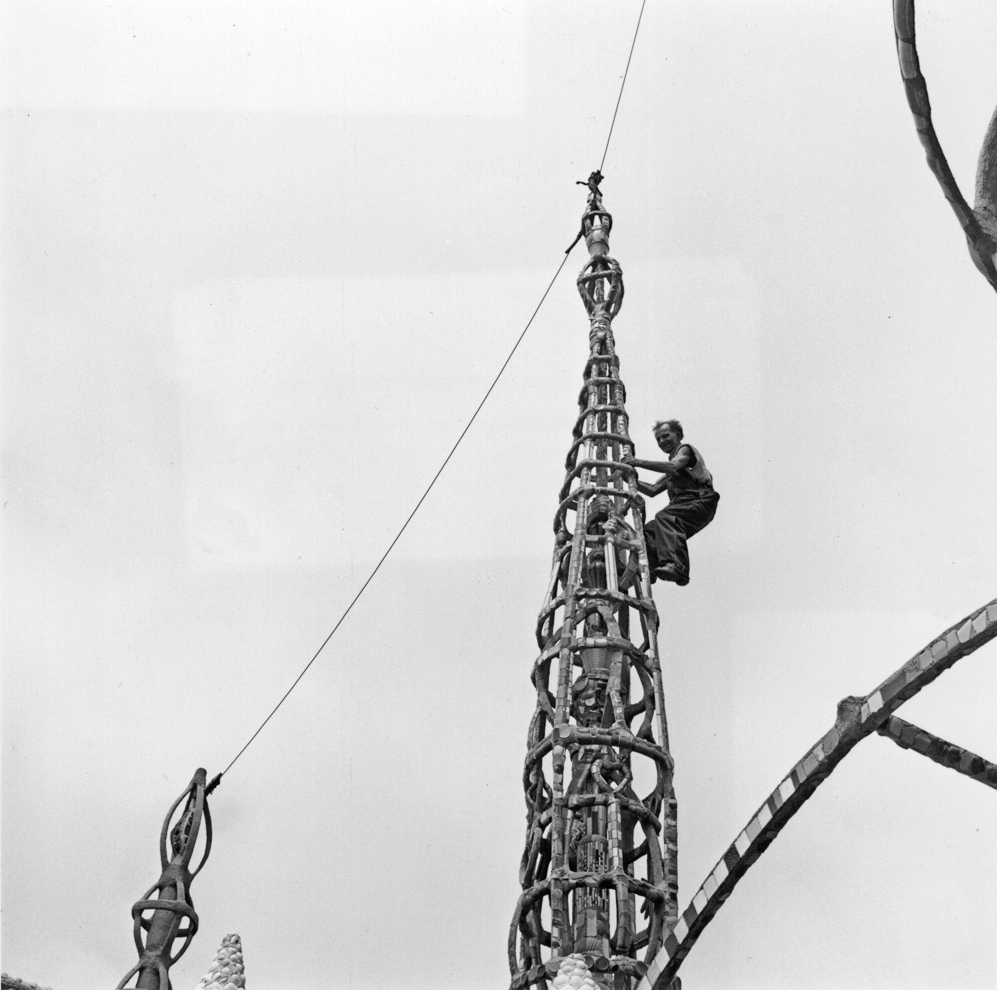 A black-and-white photo of a man climbing a spire