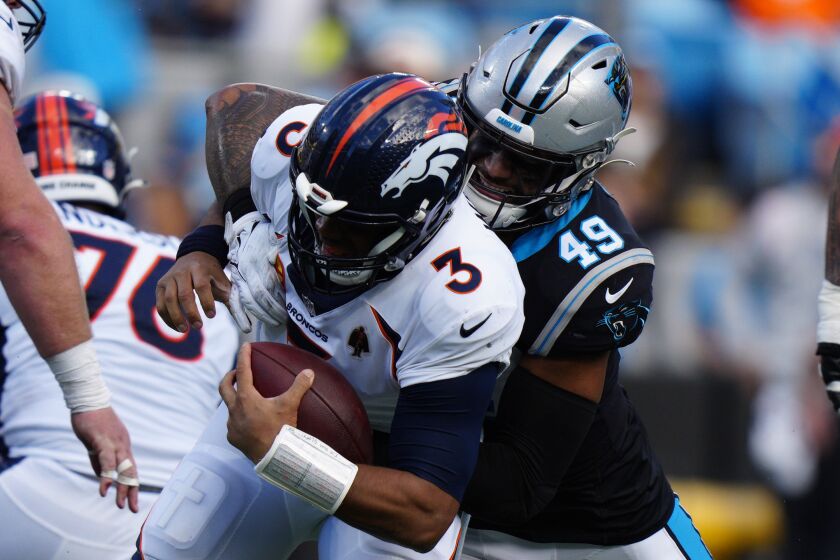 Denver Broncos quarterback Russell Wilson is tackled by Carolina Panthers linebacker Frankie Luvu during the second half of an NFL football game between the Carolina Panthers and the Denver Broncos on Sunday, Nov. 27, 2022, in Charlotte, N.C. (AP Photo/Jacob Kupferman)