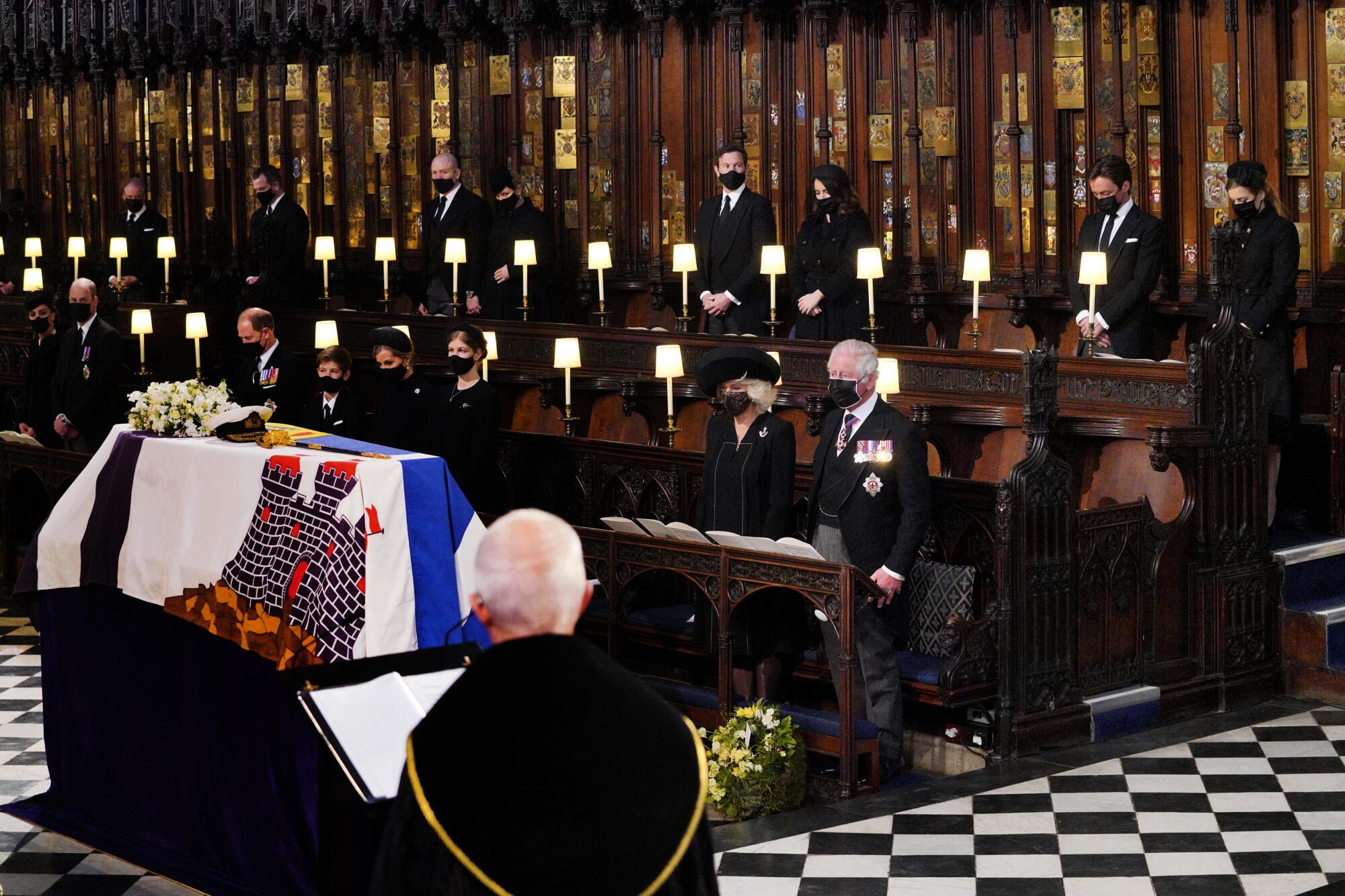 Royal family members are spaced apart in small groups in St. George's Chapel near Prince Philip's coffin.
