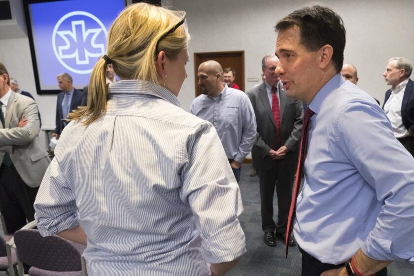 Gov, Scott Walker, right, speaks to a worker Thursday, Dec. 13, 2018, at Kimberly Clark's Cold Spring plant in Neenah, Wis. Walker executed a $28 million deal Thursday to save nearly 400 jobs at the Kimberly-Clark Corp. plant, using powers that his Democratic successor would no longer have under legislation approved last week during a lame-duck session.(Mark Hoffman/Milwaukee Journal-Sentinel via AP)