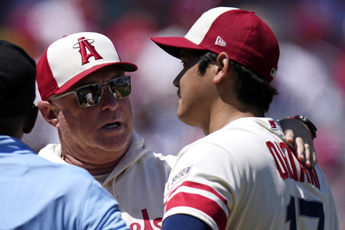Angels manager Phil Nevin, center, talks with pitcher Shohei Ohtani before taking him out of the game.