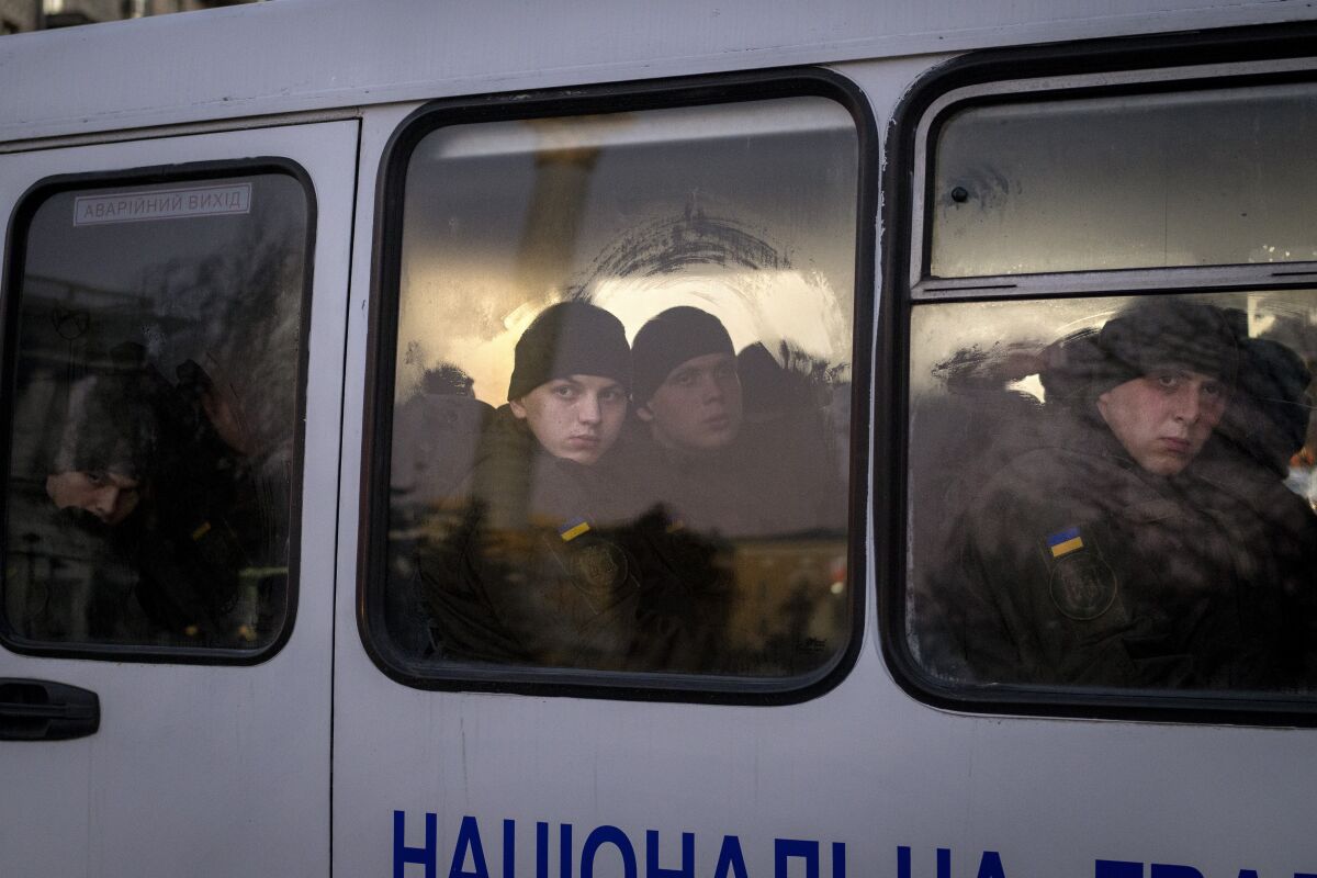 Ukraine troops look out of the window of a bus in Kyiv.