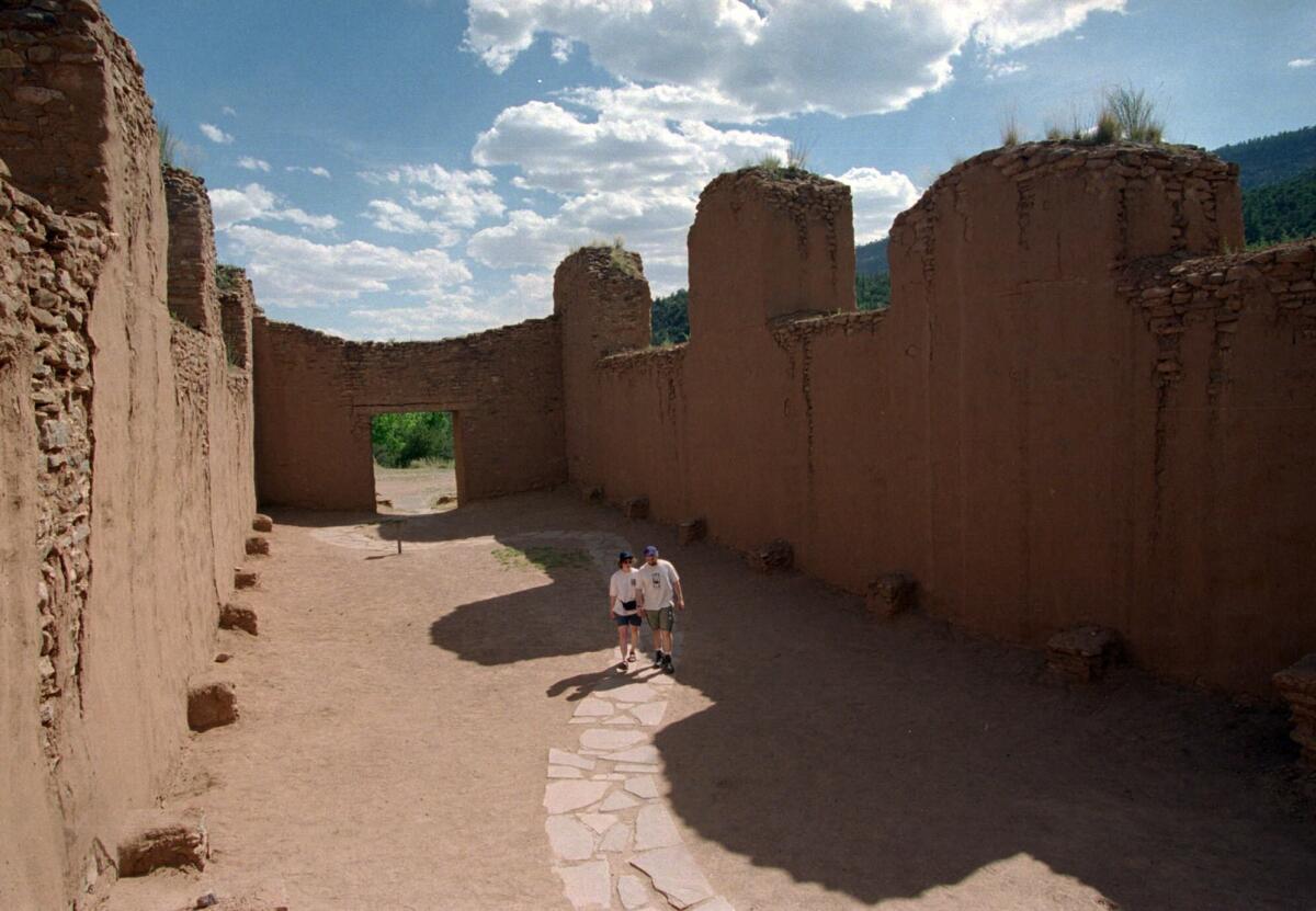 Visitors to the Bandelier National Monument in New Mexico are led along a paved footpath through the remnants of the 13th century Tyuonyi pueblo ruins.