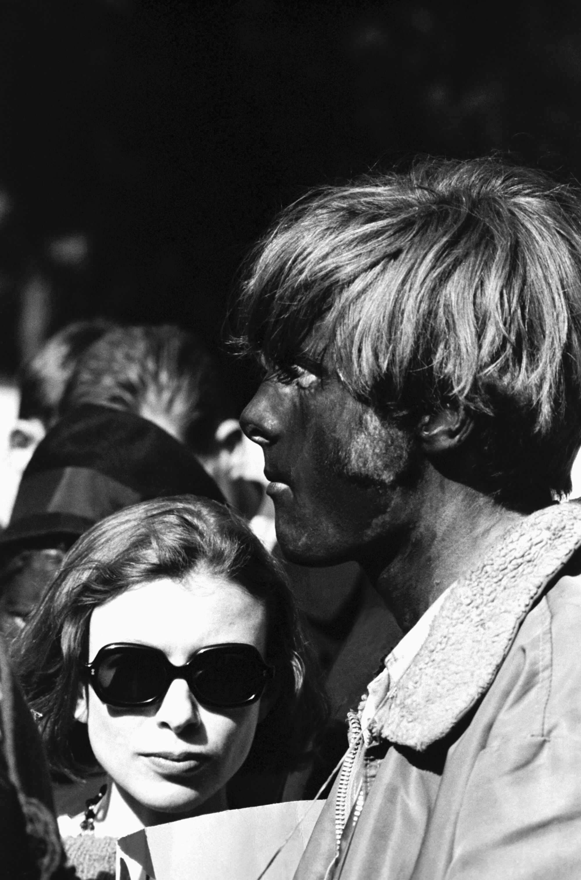 Joan Didion stands next to a man with his face painted in Golden Gate Park.