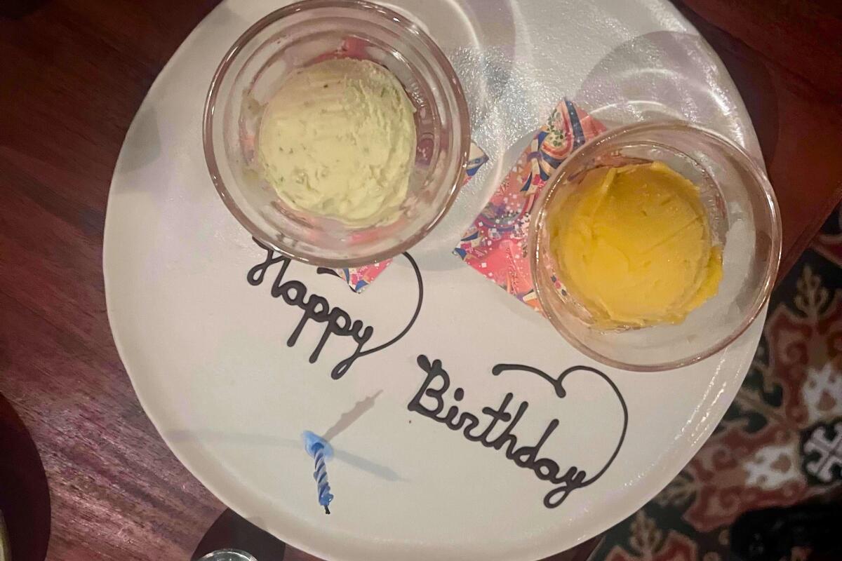A scoop of lime crème fraîche ice cream and mango sorbet on a plate with the words "Happy birthday"