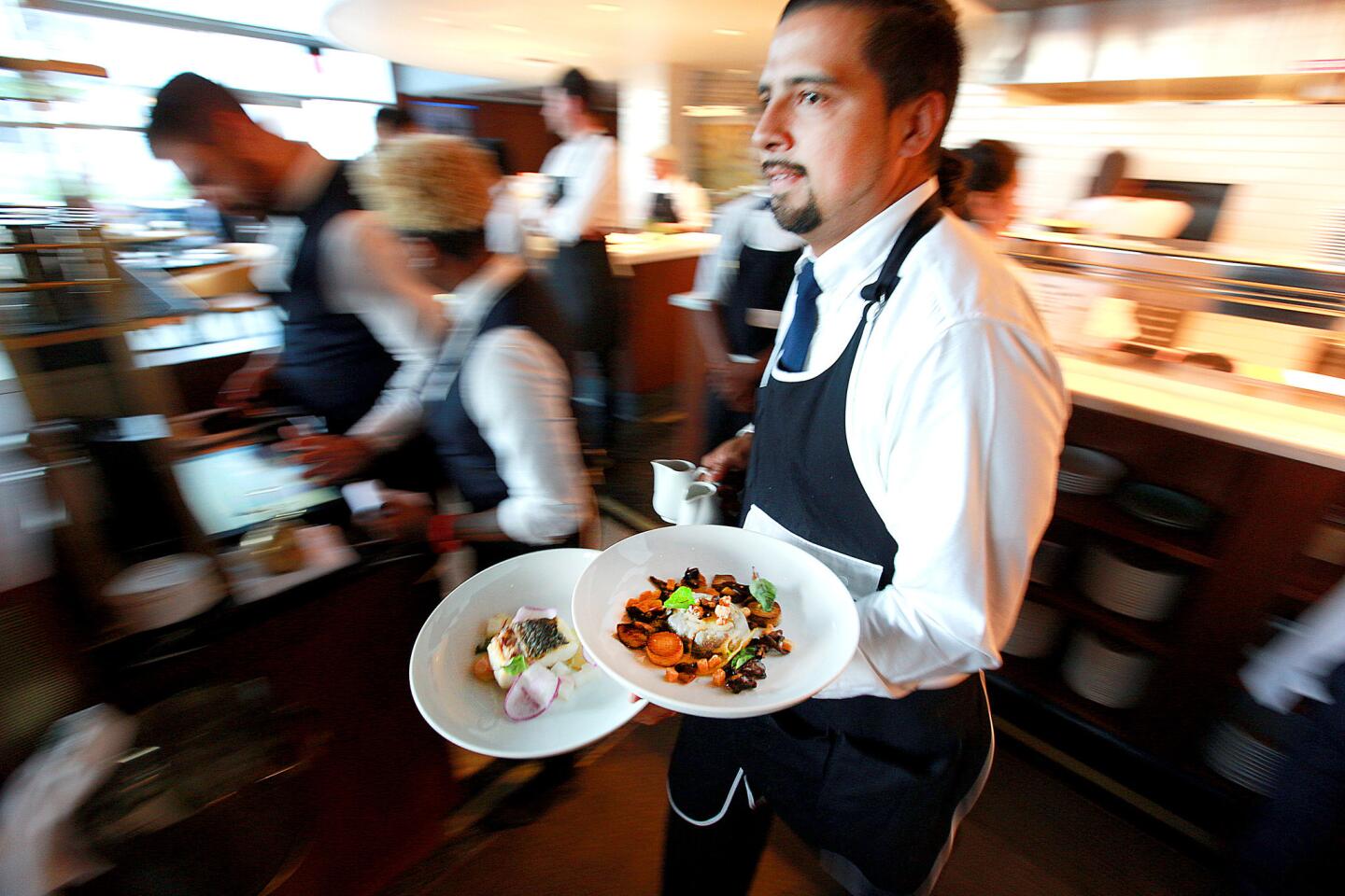 A server carries dishes to tables at Paley.