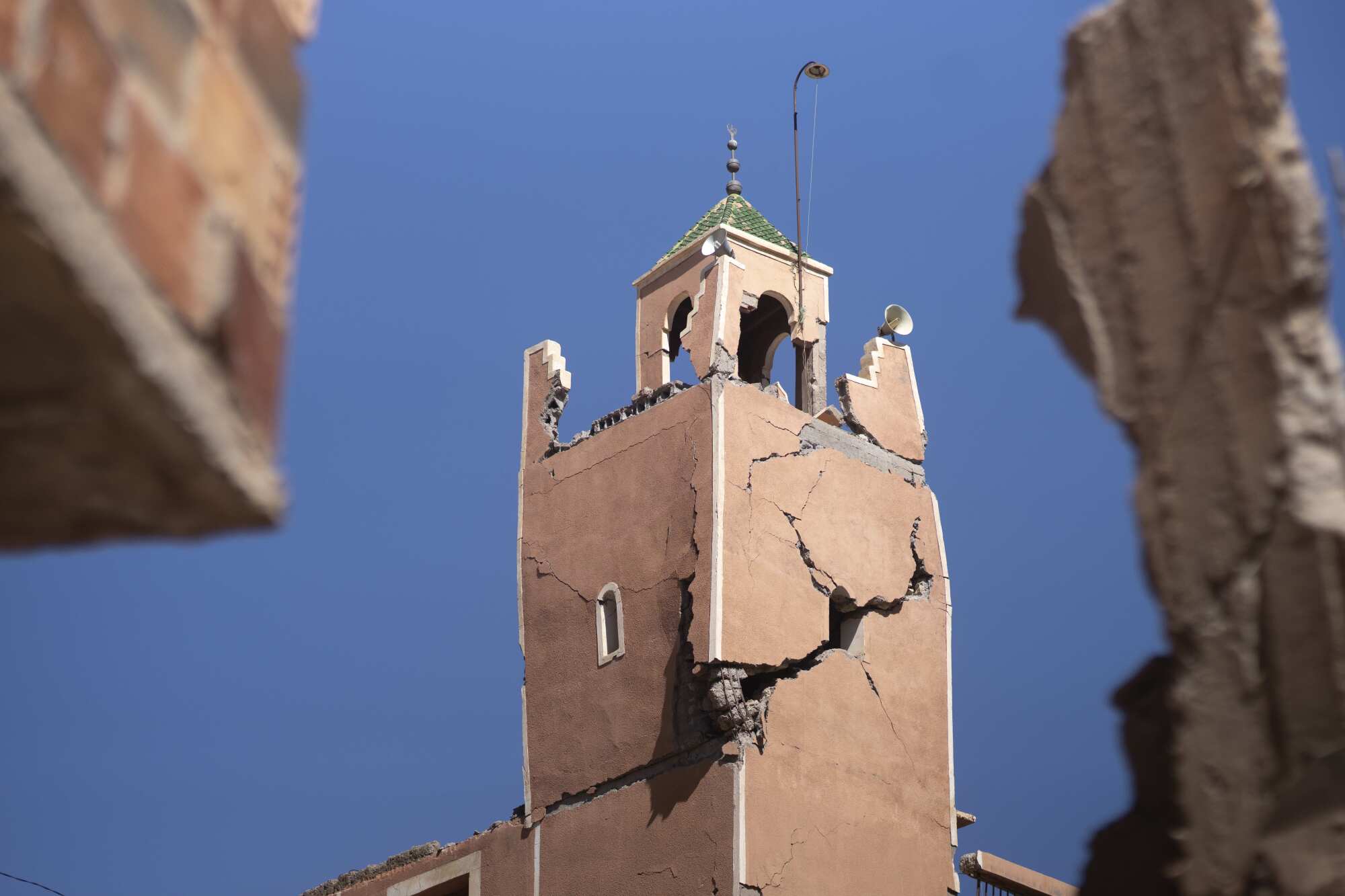A tall, historic structure is seen against a background of blue sky. The building is cracked nearly in half. 