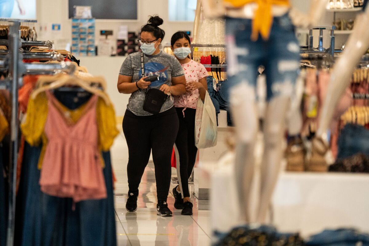 Masked shoppers browse inside Papaya while wandering the Glendale Galleria on Thursday.