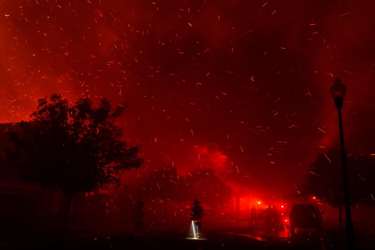 A crew fights a wildfire on a hill at night.