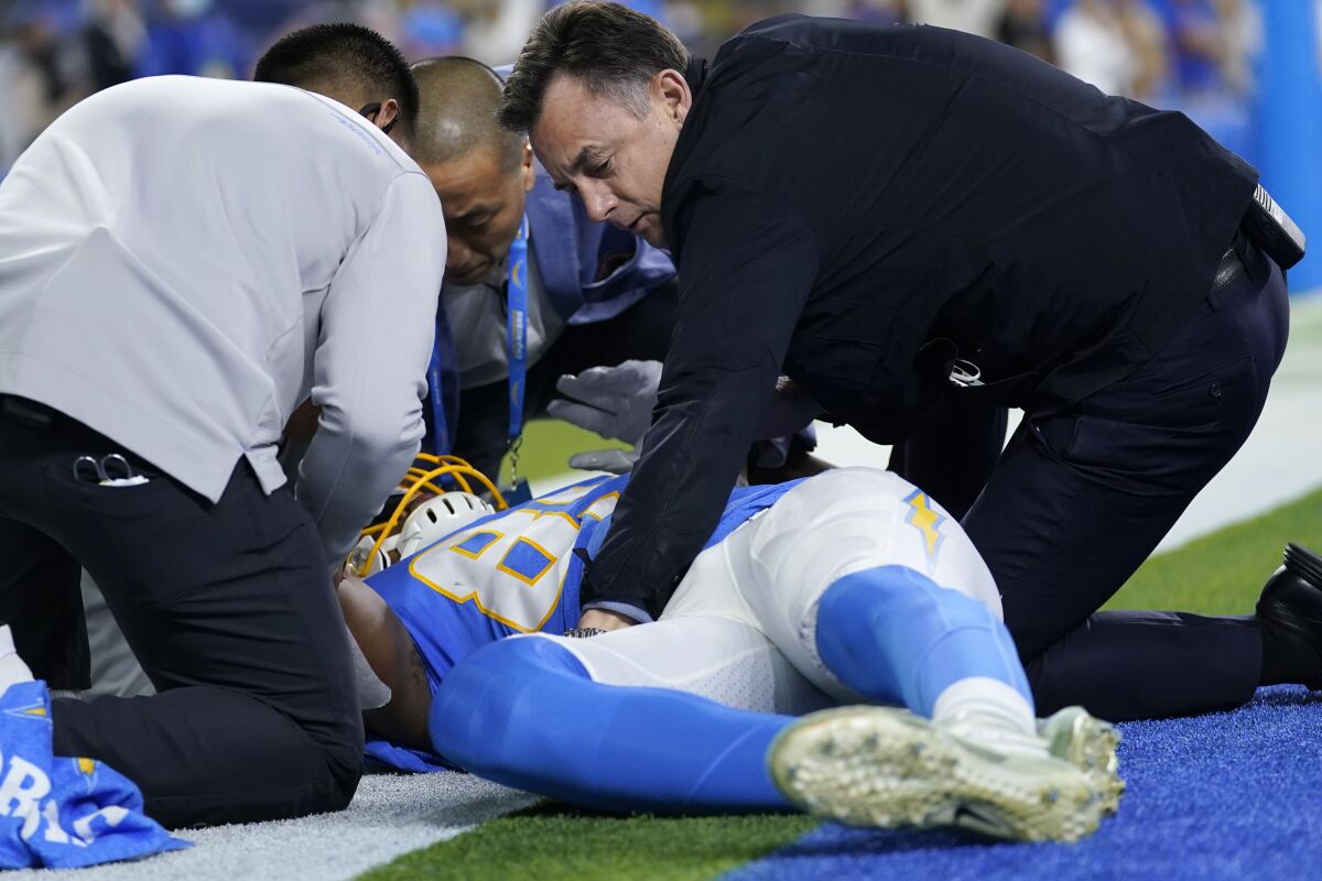 Team officials attend to Los Angeles Chargers tight end Donald Parham as he stays down after an injury during the first half of an NFL football game against the Kansas City Chiefs, Thursday, Dec. 16, 2021, in Inglewood, Calif. (AP Photo/Ashley Landis)