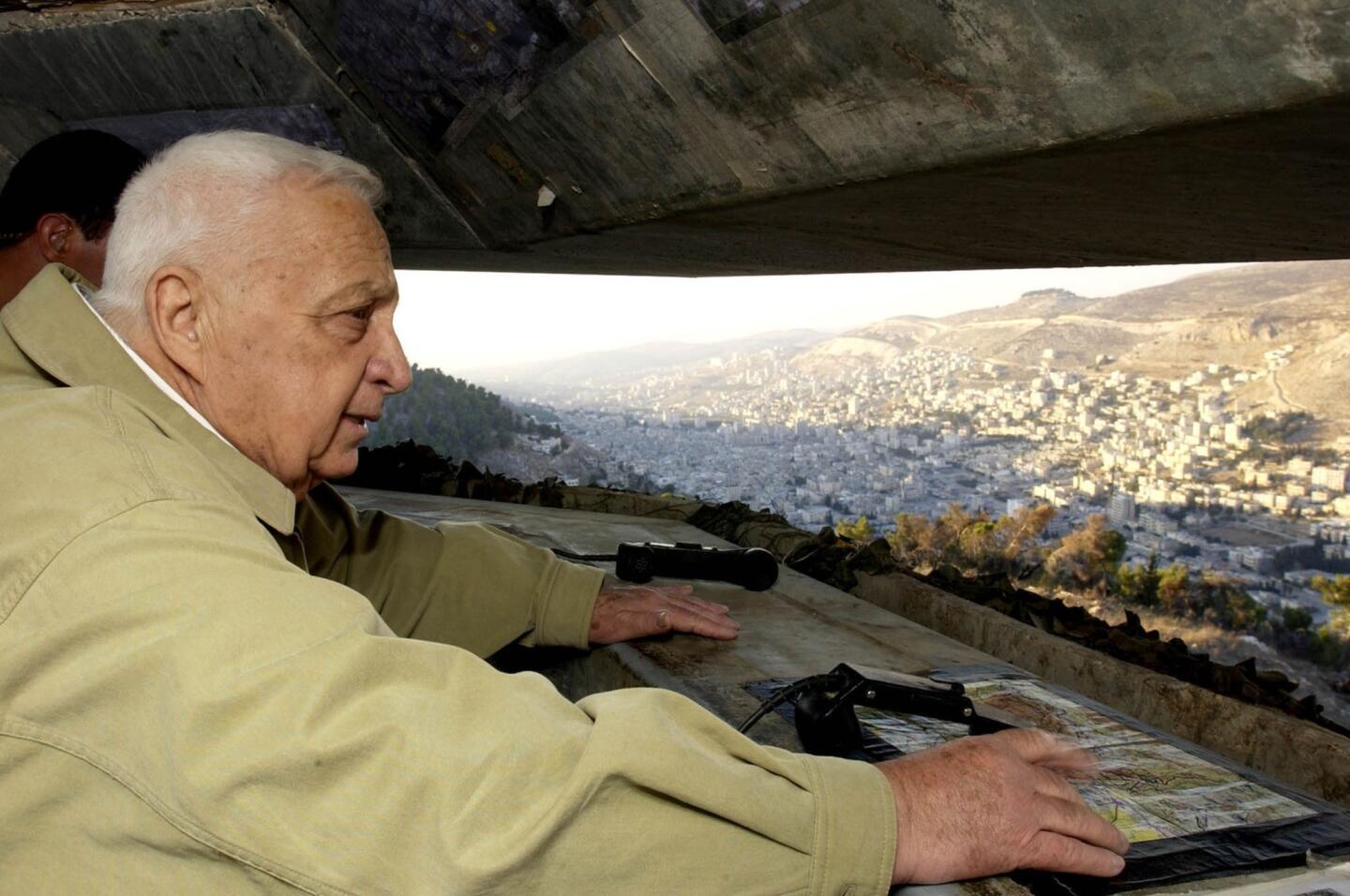 Prime Minister Sharon looks at the West Bank town of Nablus during a November 2002 visit to the Tel Fares observation point that overlooks the Palestinian town. In the spring of that year, Sharon responded to a relentless series of suicide bombings in Israeli cities with Israel's most sweeping military offensive since the 1967 war, sending the army into all the major population centers of the West Bank.