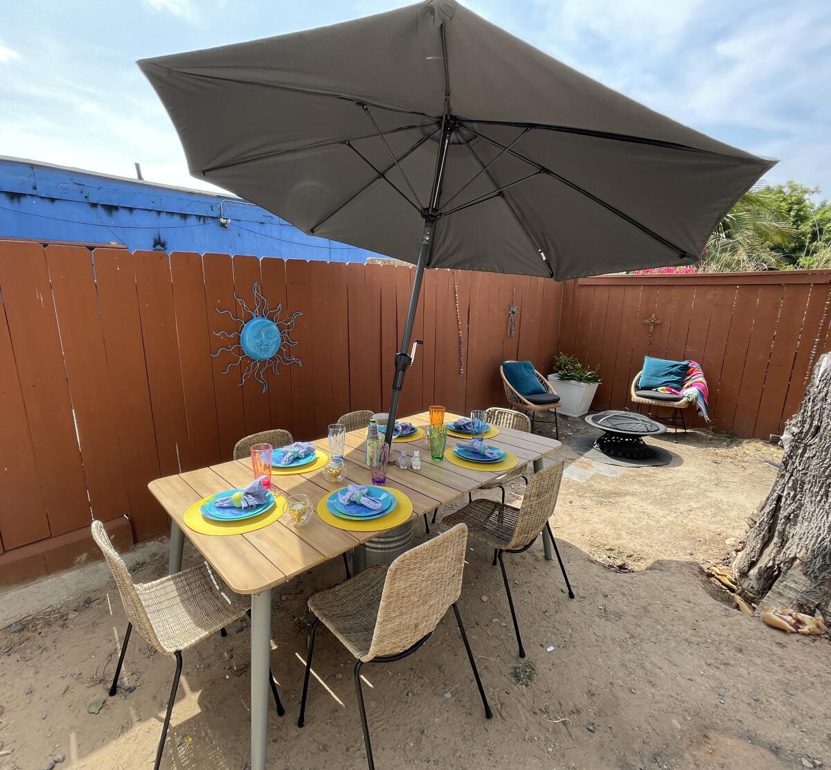 The Ibarras’ backyard has a patio dining set with umbrella and chairs around a fire pit.