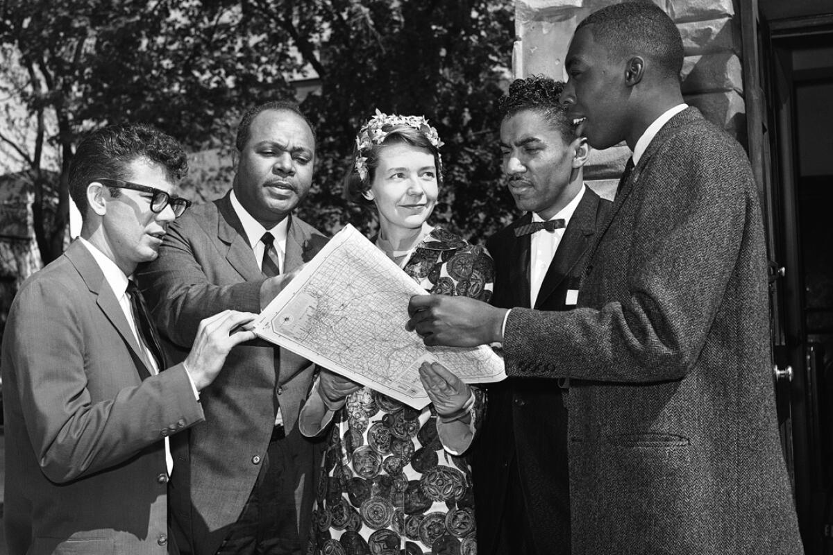 A woman and four men look over a map in 1961.