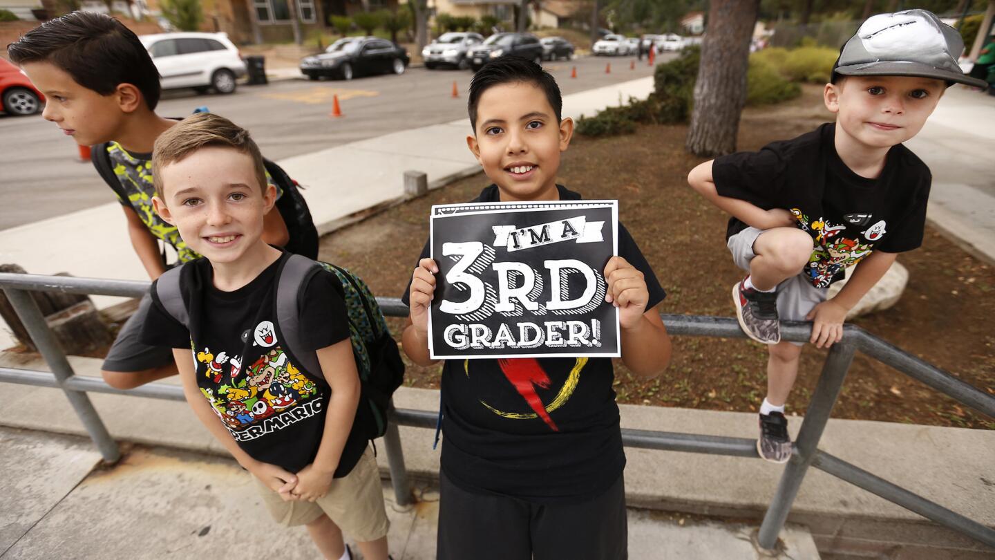 Joaquin Valdiva, center, holds his class sign with friends Jacob Ortega, Hunter Henderson and Hudson Henderson, from left, as they meet before school at Mountain View Elementary School in Tujunga.