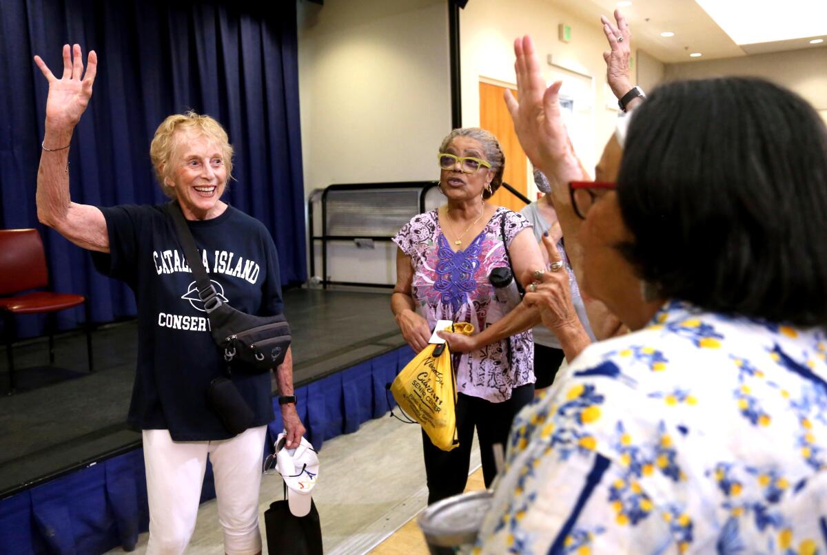 Judith Kendall, 82, left, and other seniors raise their hands saying they support 