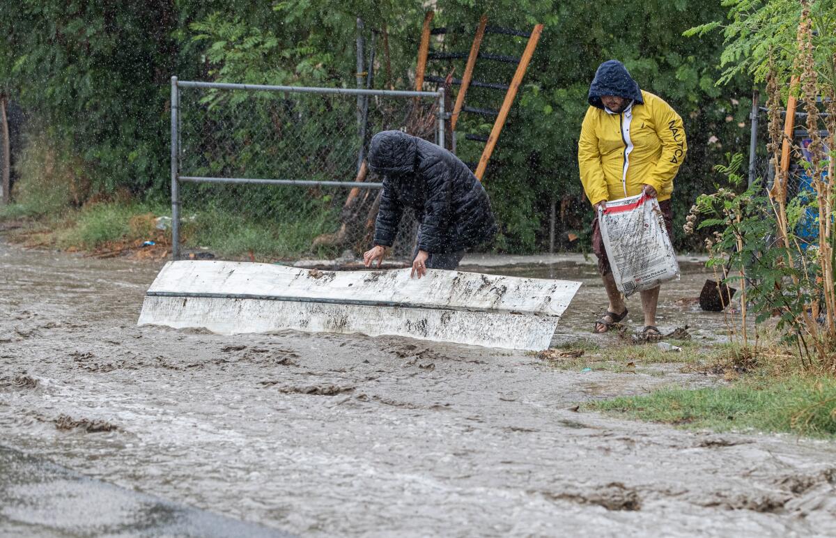 Two men work to try and to divert floodwaters.