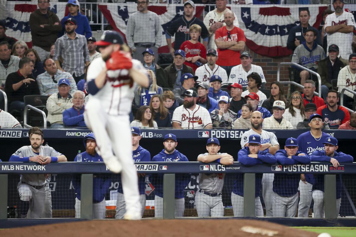 Dodgers players watch Atlanta Braves relief pitcher A.J. Minter deliver during the sixth inning.