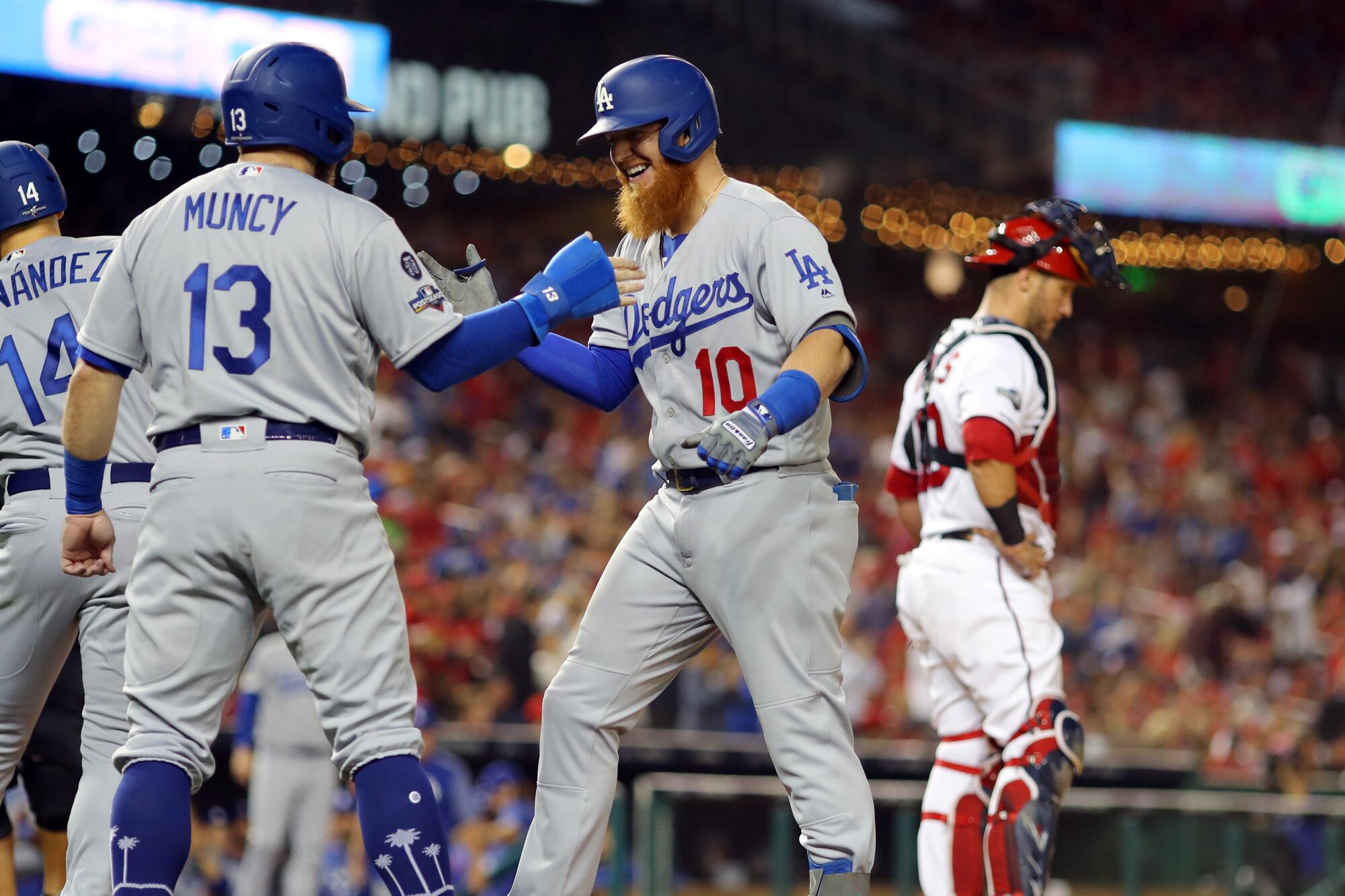 Dodgers third baseman Justin Turner, right, celebrates with teammate Max Muncy after hitting a three-run home run against the Washington Nationals in the sixth inning.