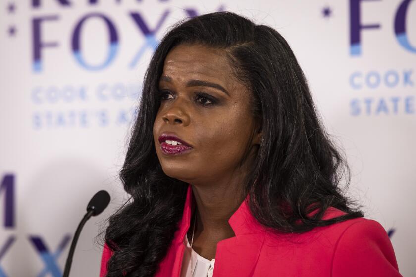 A woman in a bright blazer stands near a small microphone