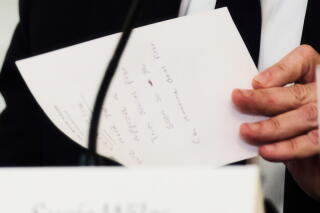 Secretary of State Marco Rubio writes a note before handing it to President Trump during a White House meeting.