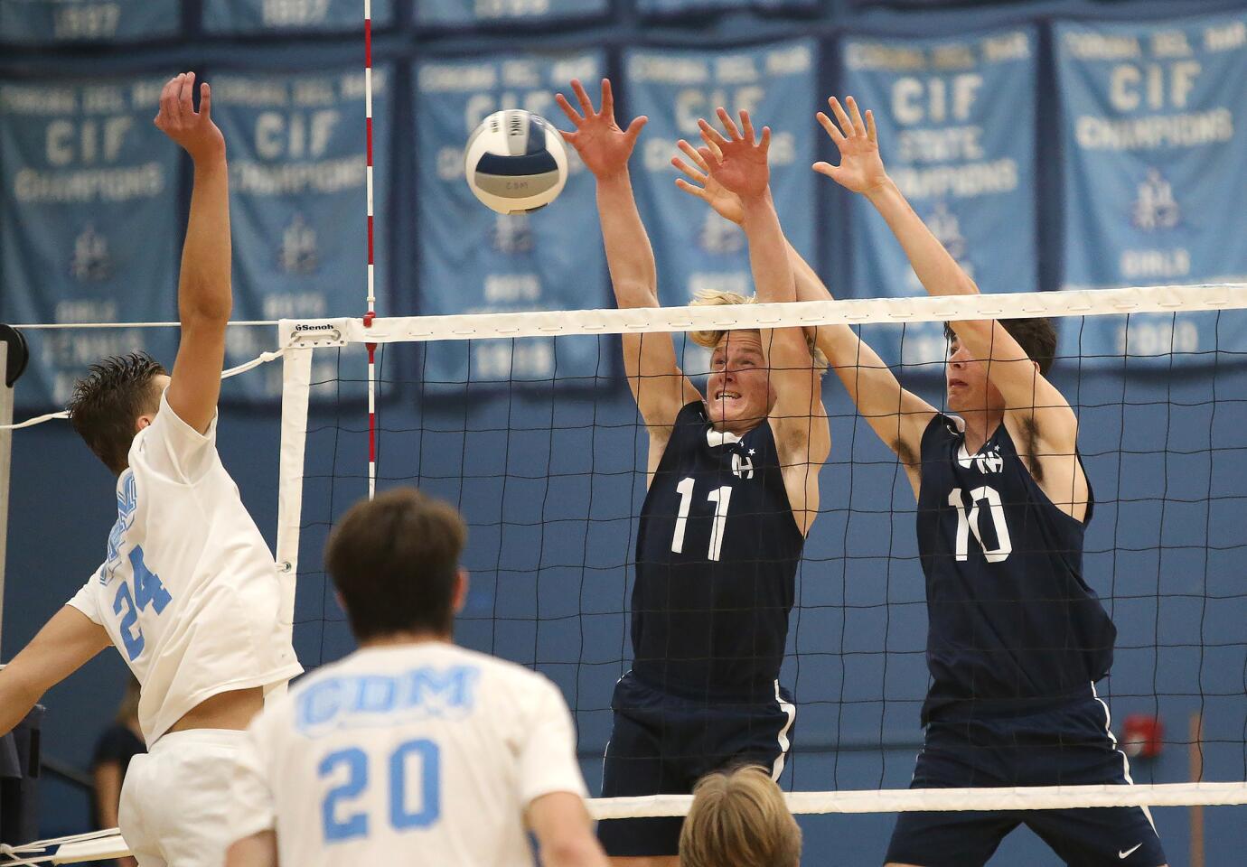 Corona Del Mar's Shane Premer (24) pokes a ball through a gap on blockers Jack Higgs (11) and Caden Garrido (10) during Battle of the Bay boys' volleyball match in Surf League play on Wednesday.