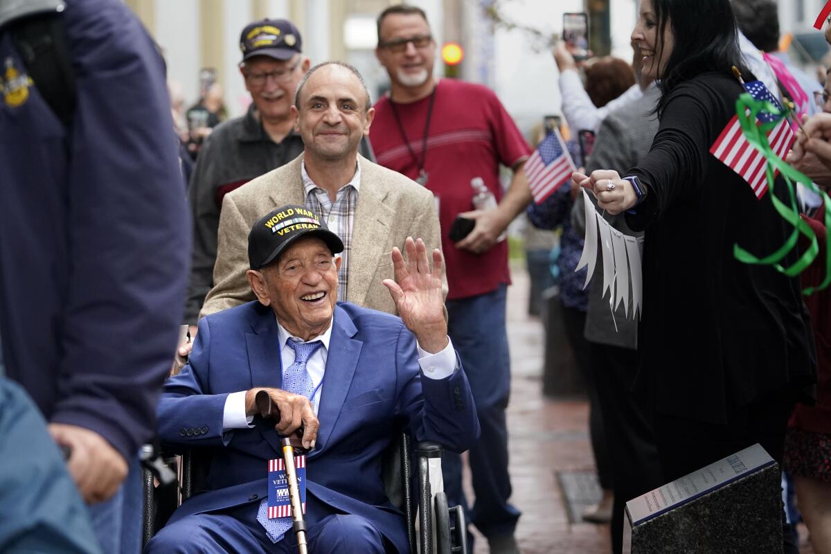 World War II veteran Joseph Eskenazi, in his wheelchair, smiles and waves