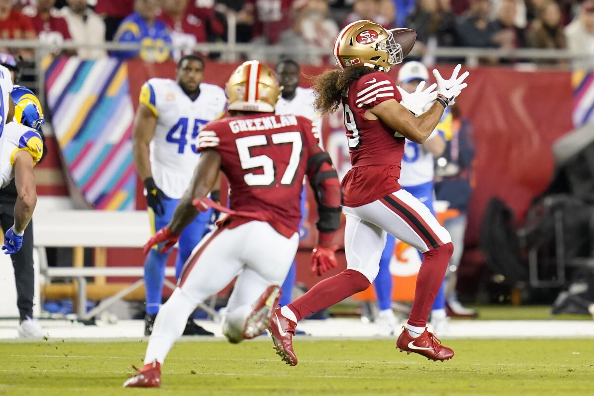 San Francisco 49ers safety Talanoa Hufanga, right, grabs an interception and returns it for a touchdown against the Rams.