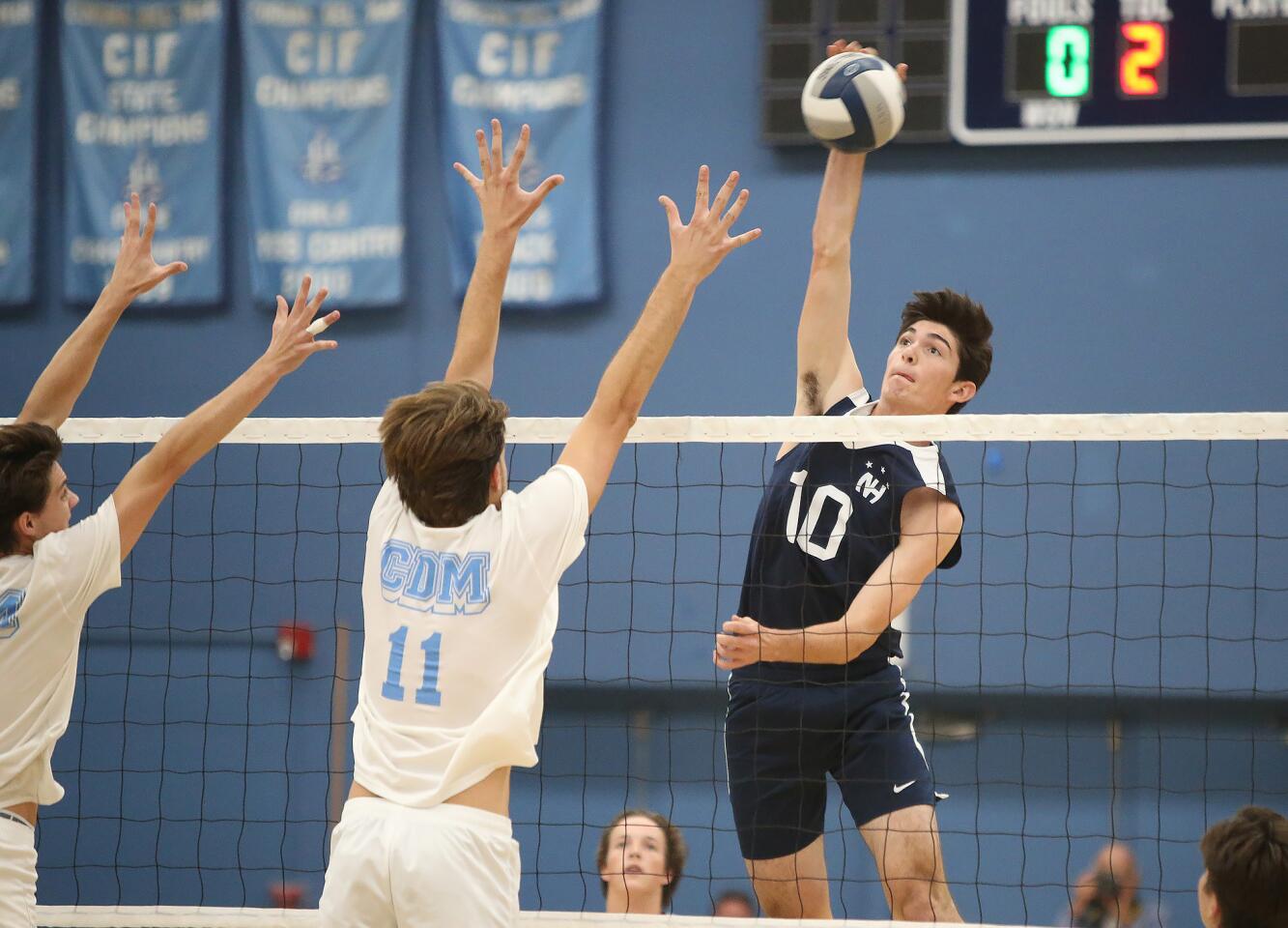 Newport Harbor's Caden Garrido (10) puts a kill past Corona Del Mar blocker Glen Linden (11) during second round of the Battle of the Bay boys' volleyball match in Surf League play on Wednesday.