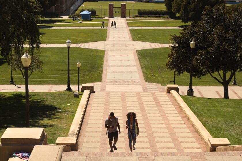 LOS ANGELES, CA - AUGUST 05, 2020 - - Chedeya Brown, 20, right, who graduated from UCLA this past Spring, and her cousin Christian Call, 24, walk up the Janss Steps on a nearly empty UCLA campus in Los Angeles on August 13, 2020. Brown returned to the campus to have her photo taken for the school yearbook. She and her cousin were going to make their own photos at the top of the stairs. The empty campus is a preview of what the Fall semester will look like. Most classes will be held online at the university due to the coronavirus pandemic. (Genaro Molina / Los Angeles Times)