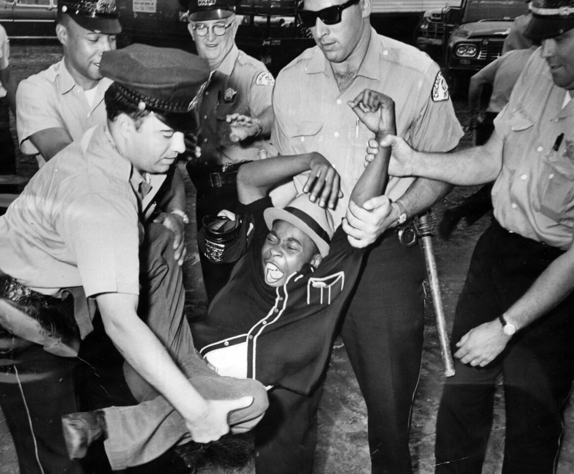 One of the demonstrators who was lying in front of a truck yells and kicks while police officers take him to a patrol wagon at the mobile classroom site at 73rd Street and Lowe Avenue on Aug. 12, 1963.