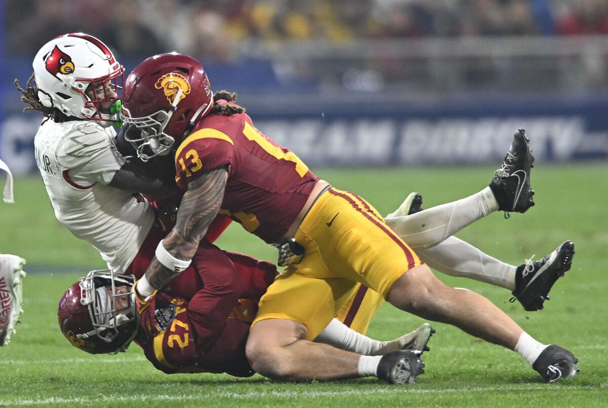 Louisville's Kevin Coleman is tackled by USC safety Bryson Shaw (27) and linebacker Mason Cobb (13) during the Holiday Bowl.