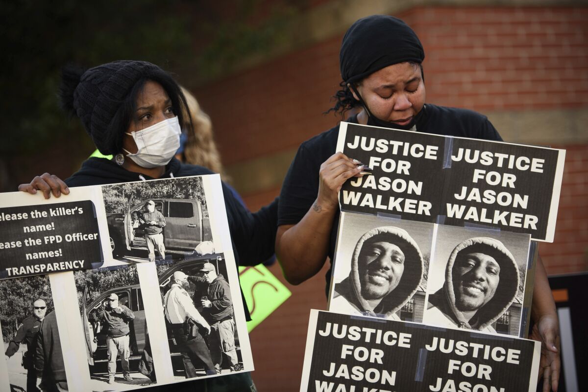 FILE - Pandora Harrington, right, cries as she holds a sign with an image of Jason Walker during a demonstration in front of the Fayetteville Police Department, Jan. 9, 2022, in Fayetteville, N.C. A judge has granted a North Carolina police chief's request to release body camera video recorded moments after last Saturday's fatal shooting of Walker by an off-duty sheriff’s deputy. The Fayetteville Observer reports that Senior Resident Superior Court Judge Jim Ammons issued his ruling Thursday, Jan. 13, 2022, two days after Fayetteville Police Chief Gina Hawkins filed the request. (Andrew Craft/The Fayetteville Observer via AP, File)