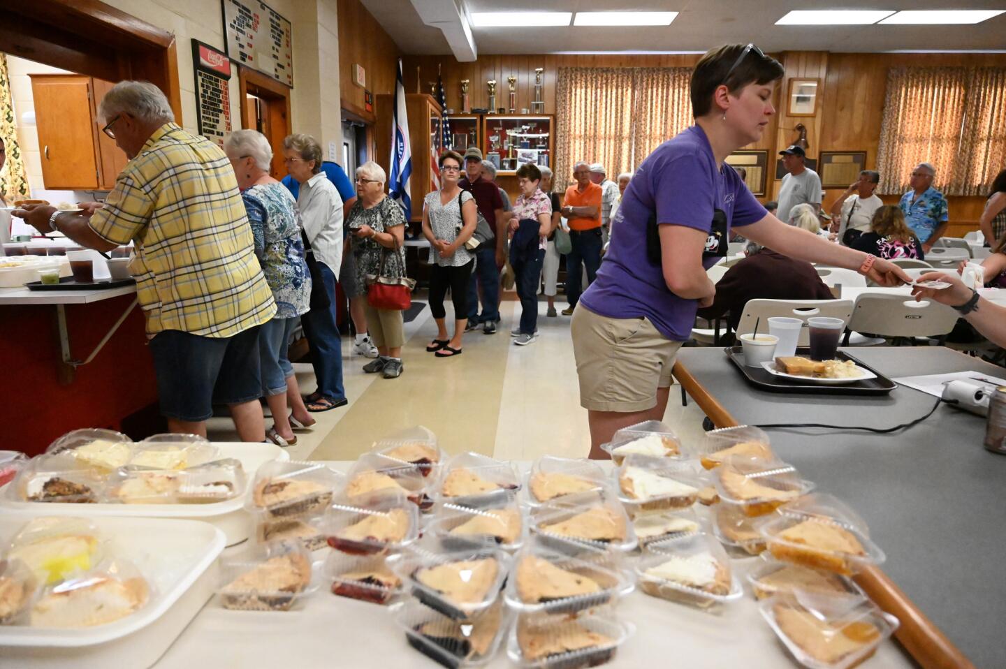 Diane Day, right, purchases a meal as a line of hungry people wait their turn during the carnival at the Harney Volunteer Fire Company on Tuesday. Day, a past resident of Harney, travelled from her current home of Charlestown, WV, to support her former community.