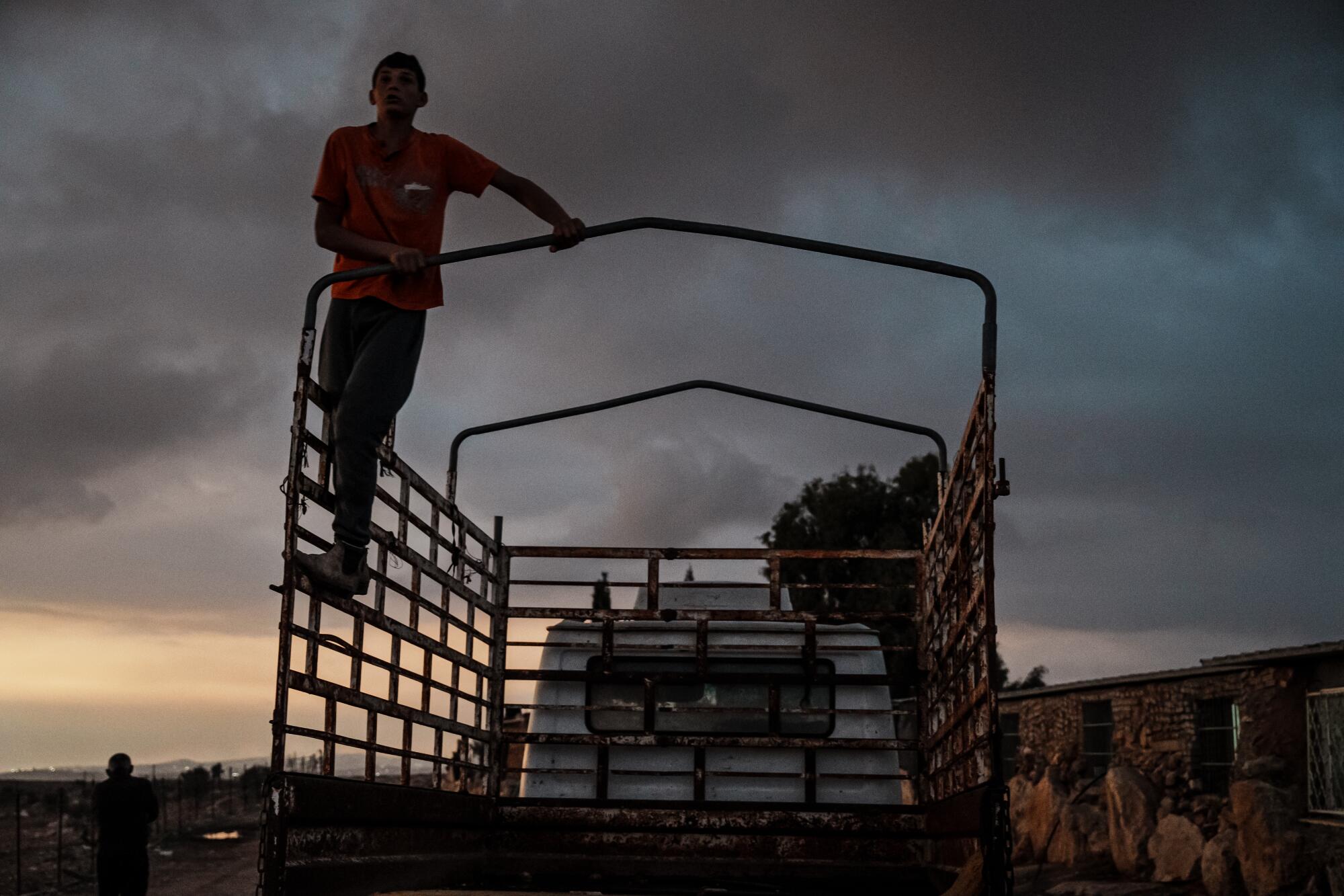 A Palestinian boy climbs to the top of the truck for a better view after neighbors announced Israeli military arriving.
