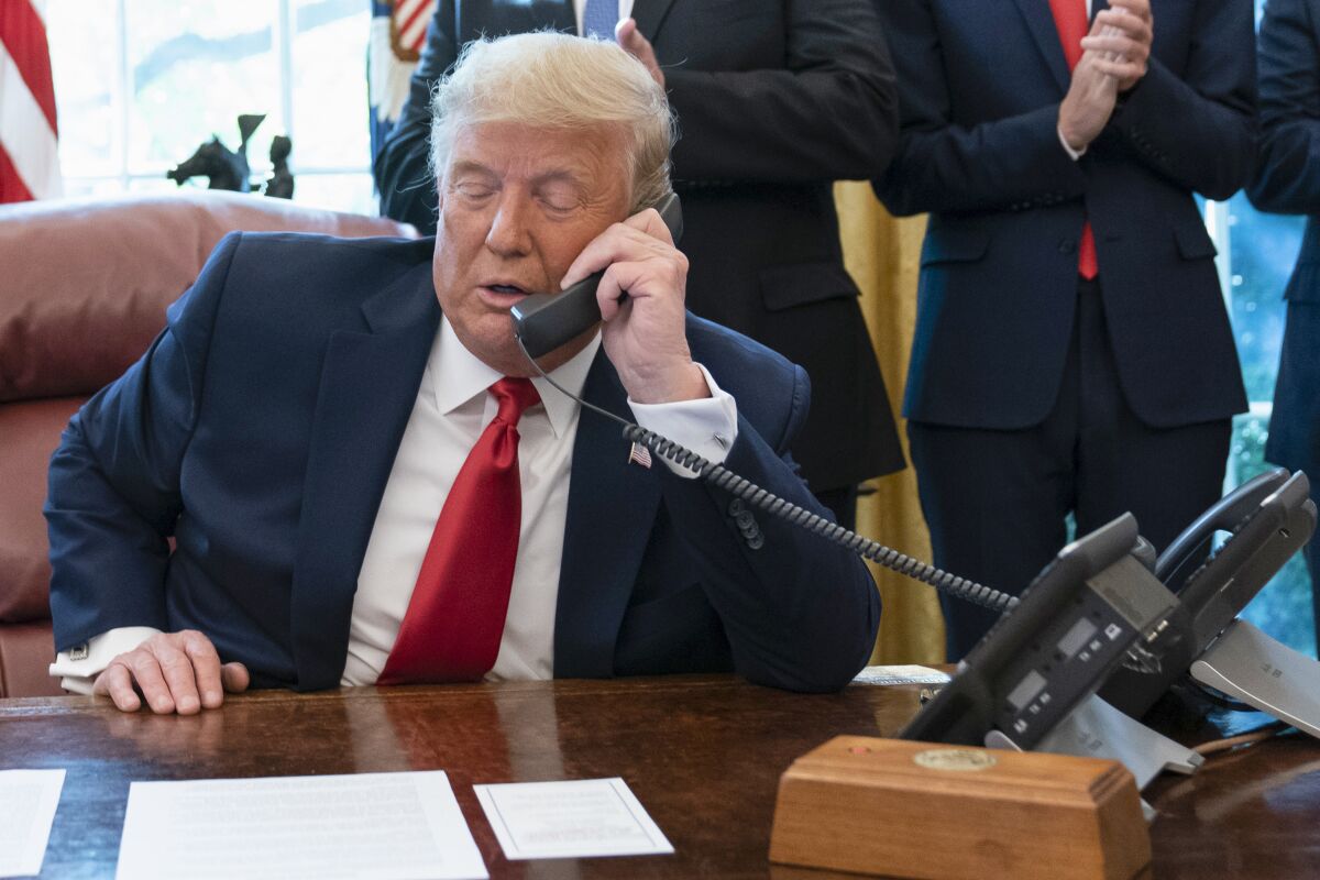 FILE - In this Oct. 23, 2020, photo, President Donald Trump talks on a phone during a call with the leaders of Sudan and Israel in the Oval Office of the White House, in Washington. White House call logs obtained so far by the House panel investigating the Jan. 6, 2021 insurrection at the Capitol do not list calls made by then-President Donald Trump as he watched the violence unfold on television. They also do not list calls made directly to the president, according to two people familiar with the probe. (AP Photo/Alex Brandon, File)