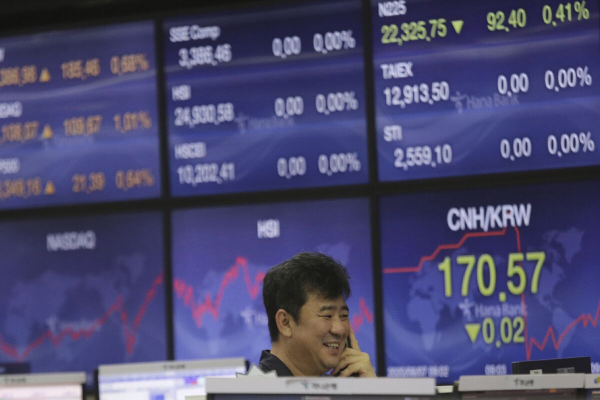 A currency trader smiles at the foreign exchange dealing room of the KEB Hana Bank headquarters in Seoul, South Korea, Friday, Aug. 7, 2020. Asian shares were mostly lower Friday in lackluster trading, as the region weighed continuing trade tensions over China and optimism about more fiscal stimulus for the ailing U.S. economy. (AP Photo/Ahn Young-joon)