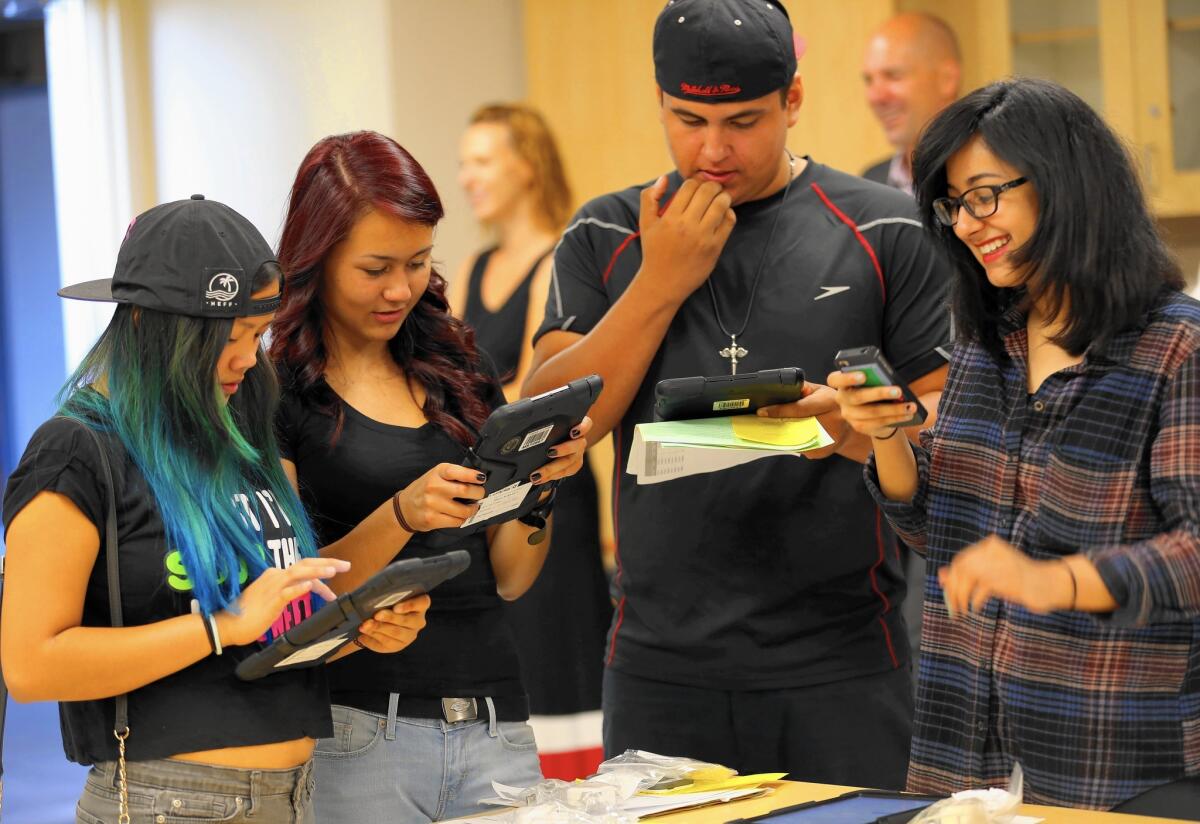 Students Jordann Ventura, 14, left, Karyna Mills, 15, Guillermo Romero, 15, and Dayanara Trujillo, 15, try out their iPads in pre-first-day orientation at Valley Academy of Arts and Sciences in Granada Hills.