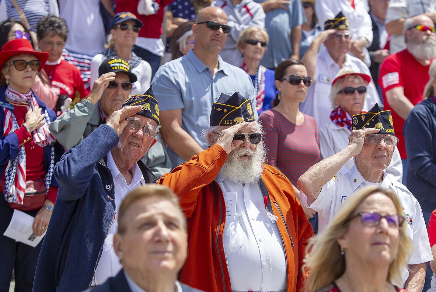 From left, Bob Lazure and Robert Spellmire, World War II veterans in the Navy, and Harlan Price, a veteran of the Air Force, salute during the playing of taps during the Huntington Beach Memorial Day ceremony Monday at the pier.
