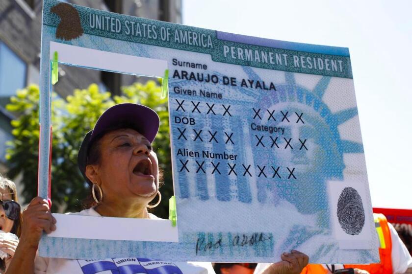 Una mujer sostiene una réplica de la 'green card' (tarjeta verde) en una marcha para exigir una reforma migratoria en Los Ángeles.