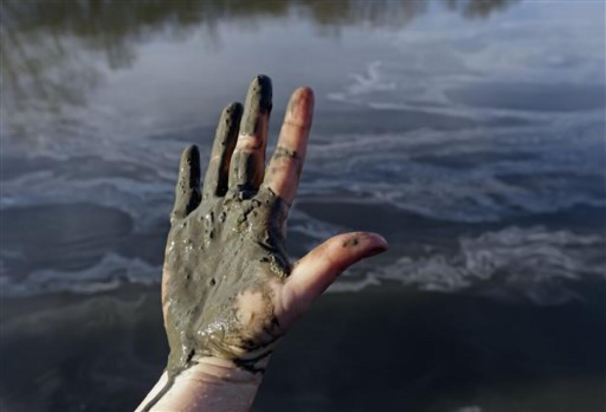 Amy Adams, North Carolina campaign coordinator with Appalachian Voices, shows her hand covered with wet coal ash from the Dan River.