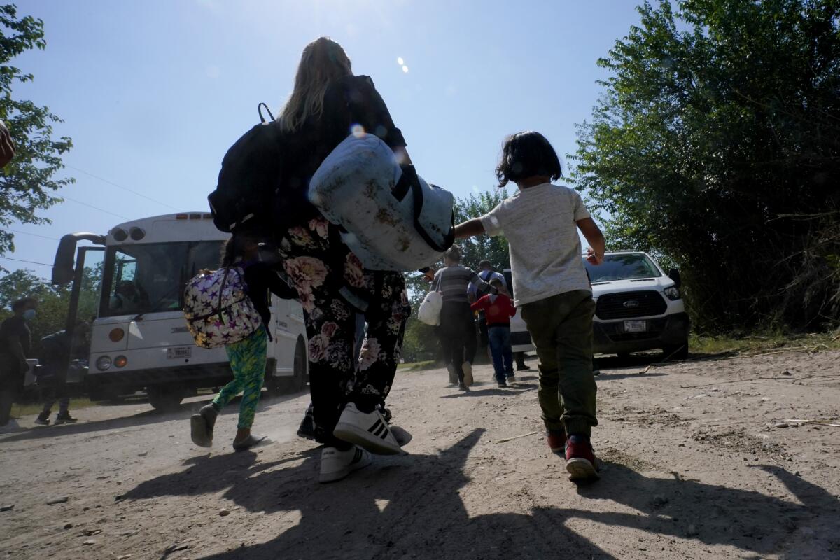 Una familia de migrantes venezolanos se dirige hacia un autobús de la Patrulla Fronteriza