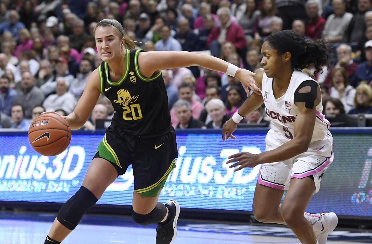 Oregon's Sabrina Ionescu, left, dribbles around Connecticut's Crystal Dangerfield in the second half on Feb. 3 in Storrs, Conn.