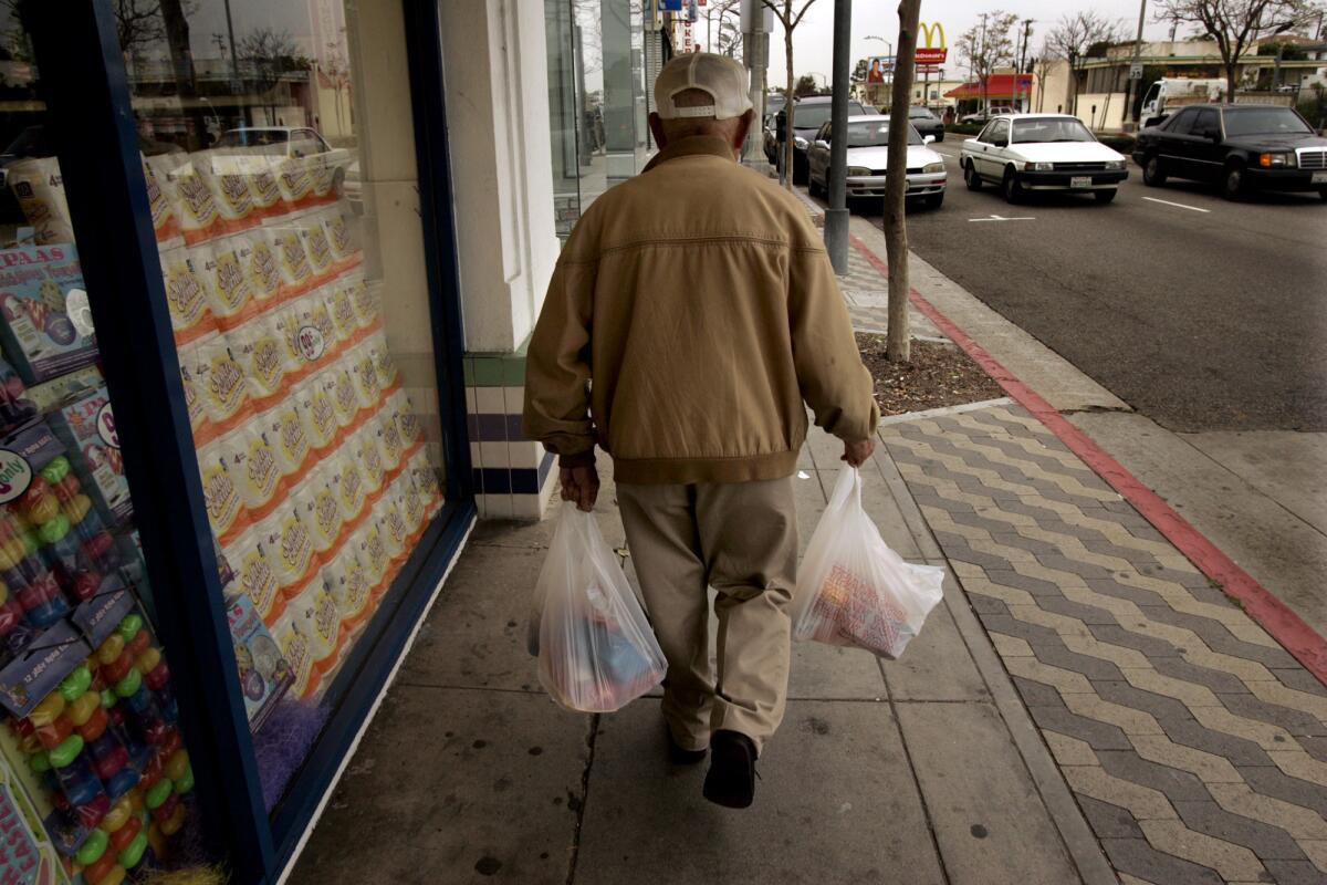 Joe Saiki, 89, walks down Pico Boulevard with plastic bags of groceries purchased in Santa Monica before the city banned such bags.
