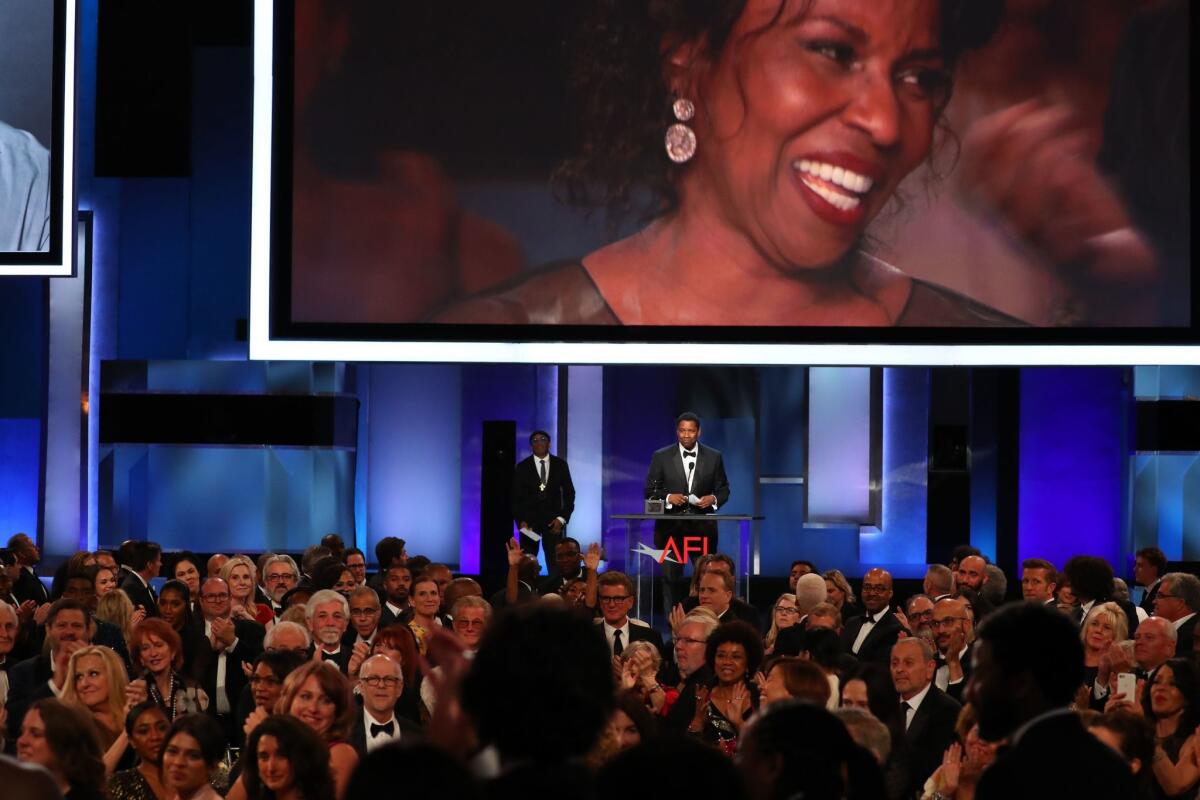 Denzel Washington applauds his wife Pauletta (on screen), as the audience gave a standing ovation.