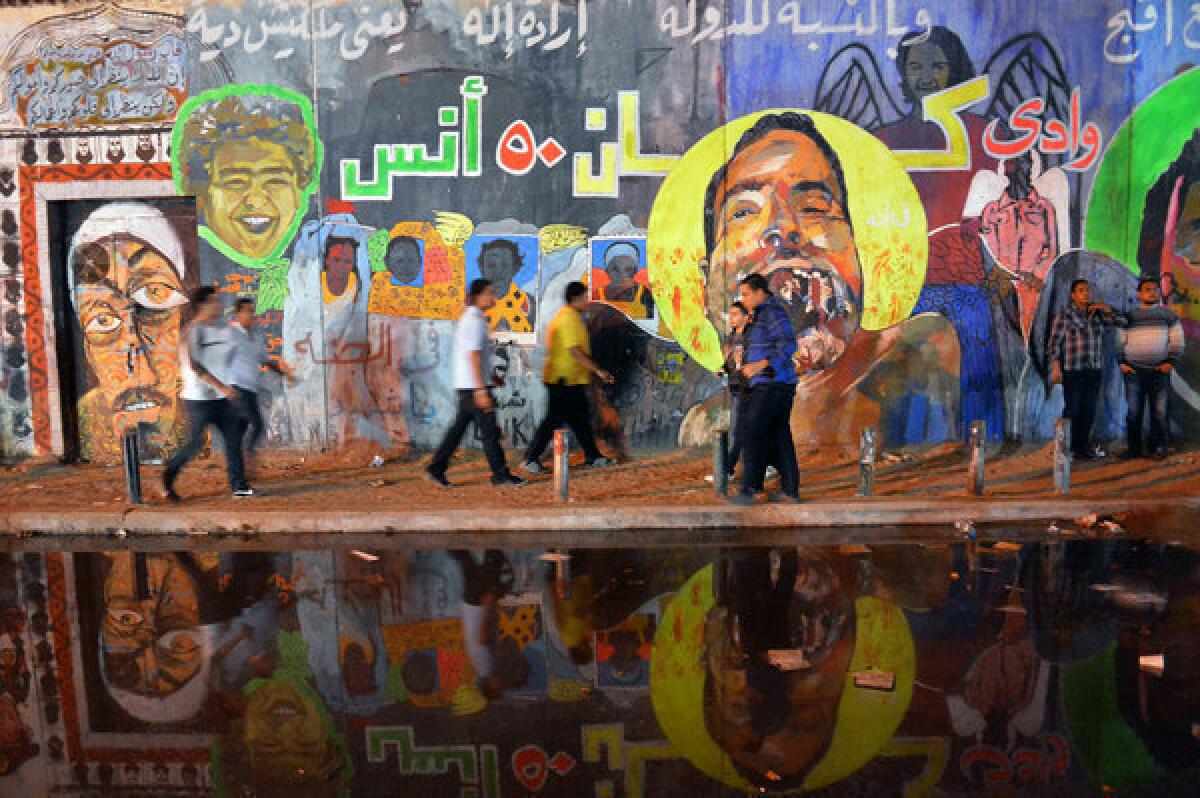 Egyptians pass by graffiti on the walls of Mohamed Mahmud Street in Cairo's landmark Tahrir Square on Nov. 30, 2012.