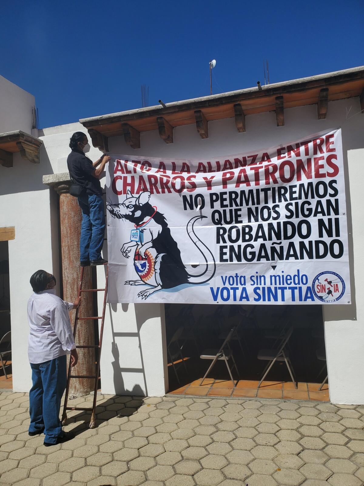 A person on a ladder attaches a sign to a wall