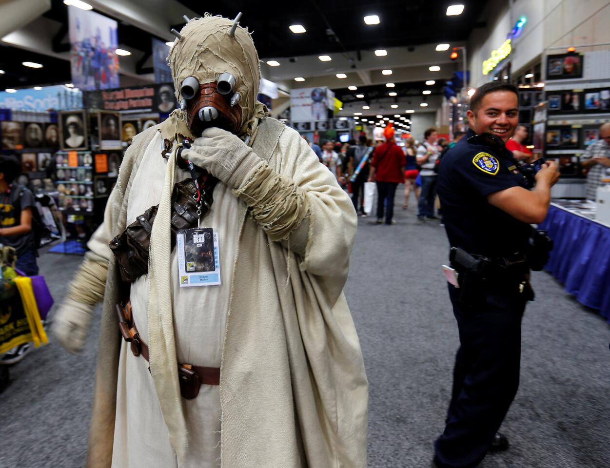 A San Diego police officer takes a second look at an attendee's Star Wars Tusken Raider costume while patrolling the convention floor during opening day of Comic-Con International in San Diego